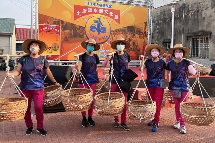 台南市仁德區大宅聖天宮18日舉辦擔水餅文化節，安排文化溯源尋根健走及擔水餅體驗，參加民眾擔起扁擔，依古禮路線繞行老街道。（郭鴻儀服務處提供）