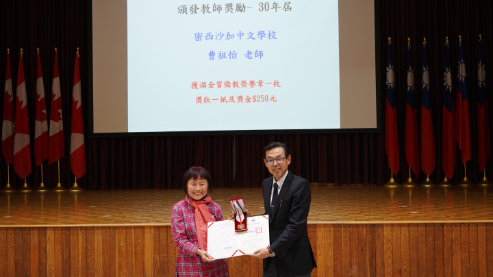 孫國祥（右一）頒發獎狀及獎章予服務滿30年密西沙加中文學校老師曹祖怡 (左)