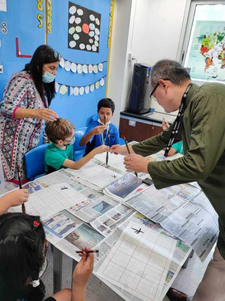 駐印度代表處教育組日前在新德里英國學校國際日活動，使用不須沾墨汁的書法水寫布教導印度學生華語與書法，讓印度學生感到很驚奇。（駐印度代表處教育組提供）
