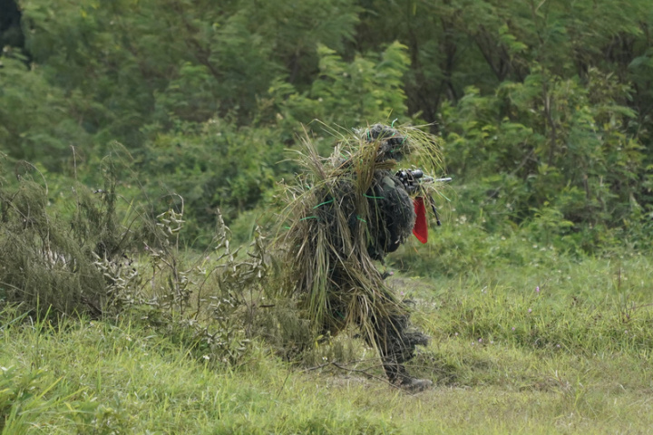 陸軍第八軍團裝甲564旅7日上午在屏東恆春三軍聯訓基地執行「三軍聯合作戰訓練測考111-5、6號 旅攻擊實彈測考」，偽裝在草叢的狙擊手完成任務後離開射擊區。