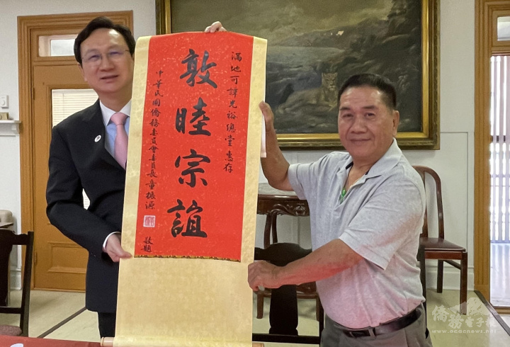 童振源（左）致贈加拿大滿地可譚光裕總堂「敦睦宗誼」掛軸，主席譚兆欽（右）代表接受