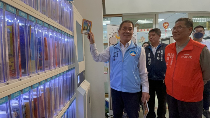 金門縣文化局在縣立圖書館設置全國第1台「智能採購書櫃」，以自動販賣機概念，讓讀者挑選有興趣的書籍，打造K-Library圖書生活便利店，金門縣政府秘書長陳祥麟（前左）28日示範操作，成功取書完成借閱。