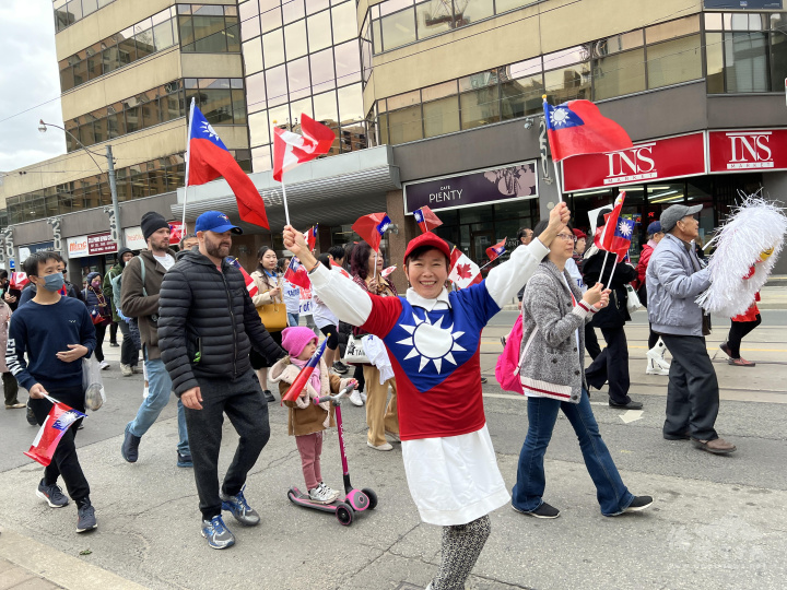 僑胞身穿國旗上衣歡樂參與全僑國慶遊行，加拿大友臺人士也帶著女兒滑著滑板車參加遊行