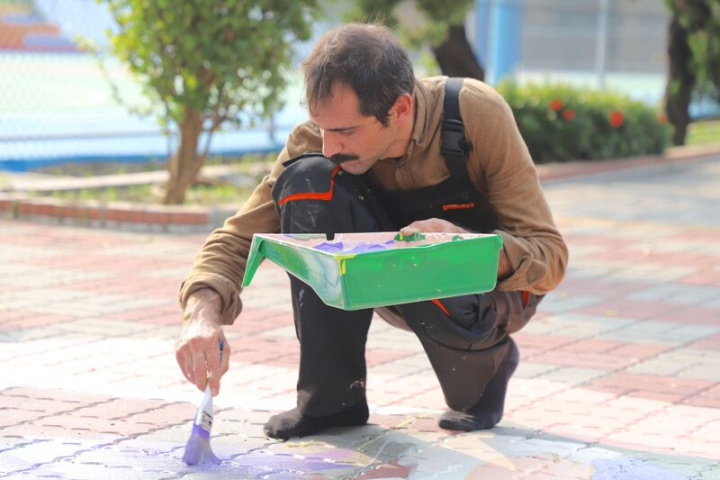土耳其藝術家法提．庫屈克（圖）赴屏東縣林邊鄉崎峰國小擔任彩繪志工，他於20日雙手分持調色皿和油漆刷進行創作。