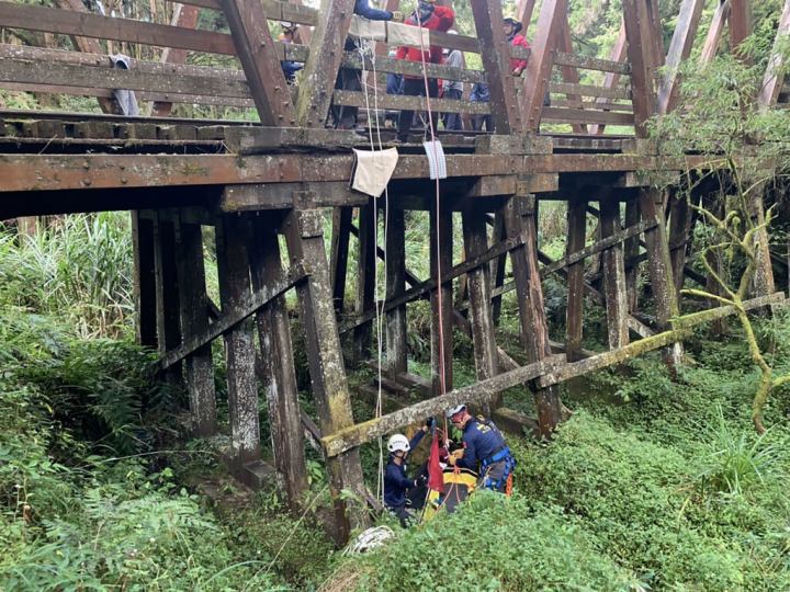 嘉義縣消防局為強化山域搜救能力，9日起一連2天在阿里山域進行山難搜救演練，勤務最後設定是在水山線靠近月台木棧道下方發現失聯民眾，搜救人員運用繩索架設、籃式擔架等器材將受困者救起，並運用阿里山分隊自製軌道台車將人送醫，過程逼真。（嘉義縣消防局提供）
