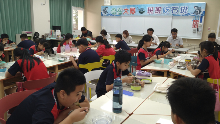 嘉義縣朴子市大同國小中央廚房7日揭牌啟用，配合行政院「班班吃石斑」政策，中午清蒸石斑魚讓師生大啖高價海鮮，縣長翁章梁（後排左4）也一起用餐。