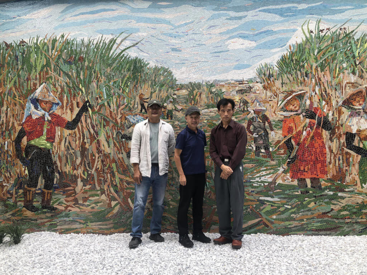 勤誠興業在嘉義縣馬稠後產業園區新廠2日落成，廠內長20公尺的馬賽克牆是藝術家歐志成（左）以畫家莊玉明（右）畫作「嘉南平原」為樣本打造作品，呈現此處未開發前的甘蔗園風光。（莊玉明提供）