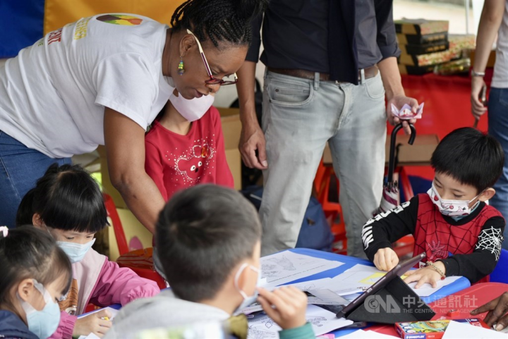​​A Caribbean teacher of English leads Taiwanese children through activities at the Embassy of Saint Vincent and the Grenadines reading booth. 