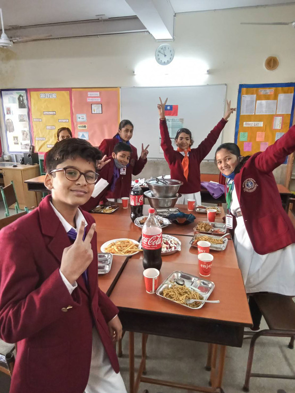 位於德里的布魯貝爾斯國際學校（Bluebells School International），學生享用台灣教師何玫資準備的炒麵及水餃等台灣常見的食物，歡度小年夜。（駐印度代表處教育組提供）