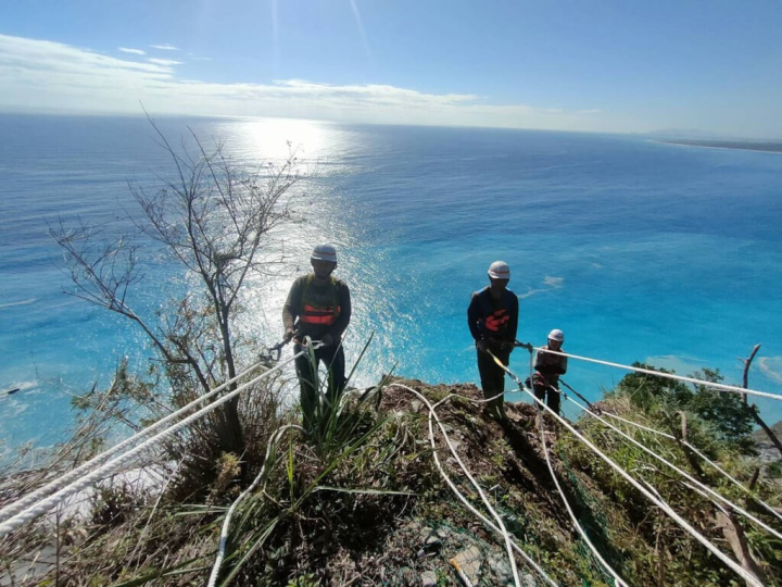 Directorate General of Highways maintenance workers known as “spidermen” rappel down a mountain slope to carry out repair work with the Pacific Ocean in the background. Photo courtesy of the Directorate General of Highways.