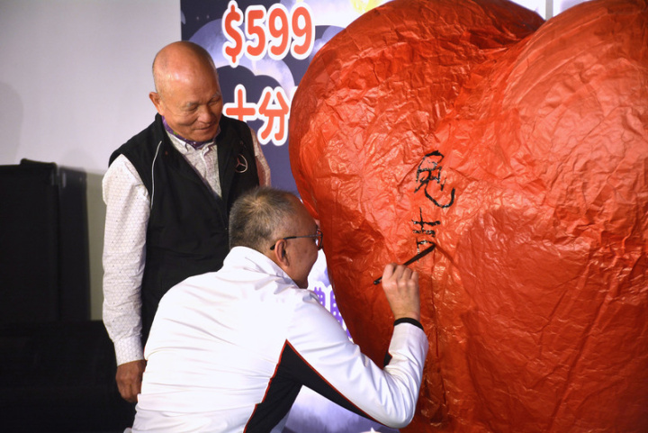 新北市副市長謝政達（右）11日出席2023新北市平溪天燈節記者會，現場揮毫在心型天燈上寫下新年吉祥話。左為天燈師傅胡民樹。