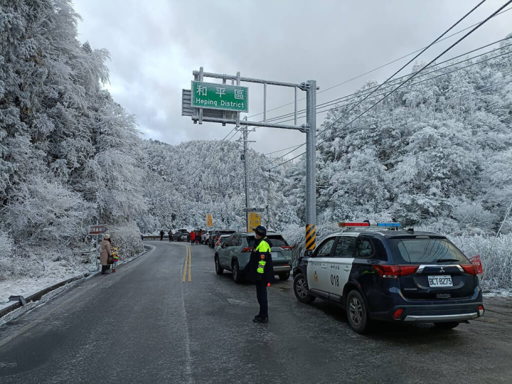 台7甲線45.7K附近27日晚上飄雪，台中市警察局和平分局員警28日在與宜蘭交界處進行交管，呼籲遊客上山在結冰處需加掛雪鏈行駛避免打滑。（警方提供）