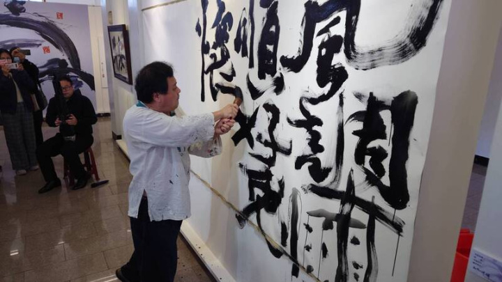 嘉義縣新港奉天宮10日邀請意象書法家陳世憲（前）舉辦「大地祈願」書法展，陳世憲現場揮毫，在牆上書寫「風調雨順好兔懷德，離新冠迎安康」，祈願台灣早日走出COVID-19疫情。