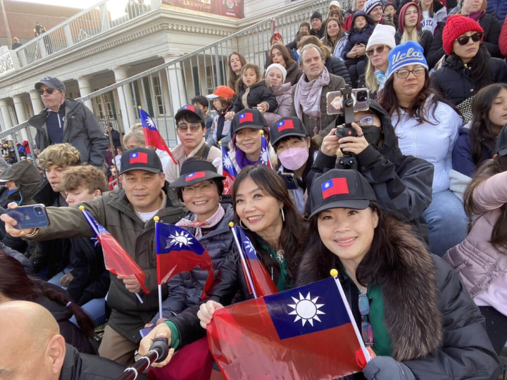 北一女校友陳鳳桃（右）、駐洛杉磯辦事處長黃敏境（右4）與僑胞2日在玫瑰花車遊行的觀眾席上舉國旗為北一女樂儀旗隊打氣。（陳鳳桃提供