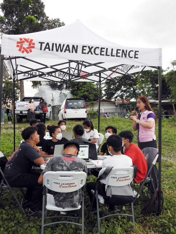 在經濟部貿易局支持下，外貿協會與台灣精品得獎廠商合作，打造行動教室小卡車開進菲律賓偏鄉，造福中輟的菲國民眾。圖為失學年輕人透過行動教室上課。
