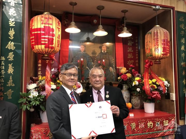 駐紐約辦事處處長李光章(左)代表僑務委員會委員長童振源頒發賀狀給主席黃韶鈞、黃建中(右)