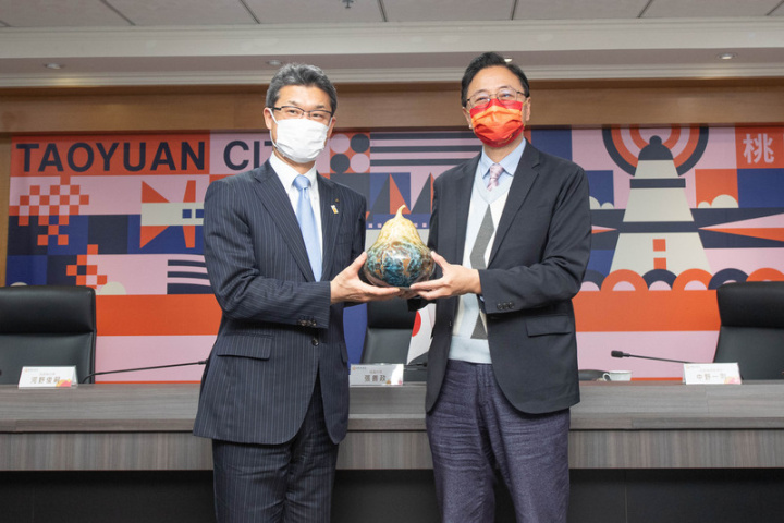 桃園市長張善政（右）與來訪的日本宮崎縣知事河野俊嗣（左）及代表團進行交流，並致贈台灣京瓷山水瓶作為紀念禮品。
