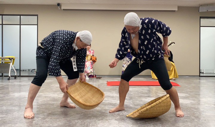 新北市新店區7日與日本島根縣安來市簽「友好交流都市備忘錄」，日本島根縣安來市長田中武夫（左）穿上漁民服飾，腰繫魚籠、手拿竹簍，跳起泥鰍舞，場面逗趣。