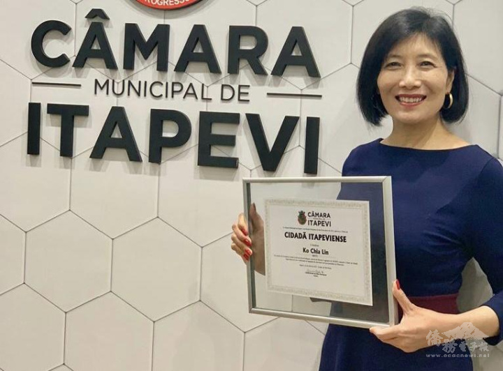 柯家玲醫生拿著榮譽市民證書在Itapevi市議會招牌前合照