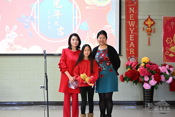 洛麗中文學校校長陳翰儀（左)，家長會會長簡惠貞，和摸彩得到大金兔玩偶學生合影。