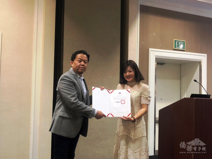 蕭蓓如(右)代表僑委會致頒賀狀給新任會長陳昭文(左)。