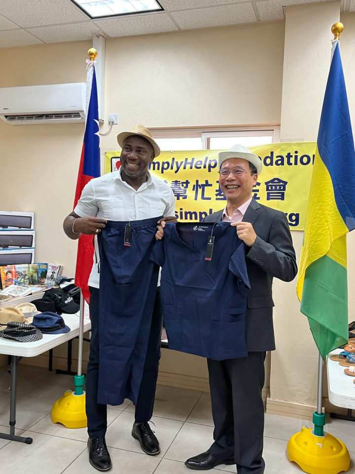 聖國社會部長布魯斯特(Hon. Orando Brewster)及我駐聖國大使藍夏禮展示幫幫忙基金會本次貨櫃捐贈之全新帽子及醫療工作服。