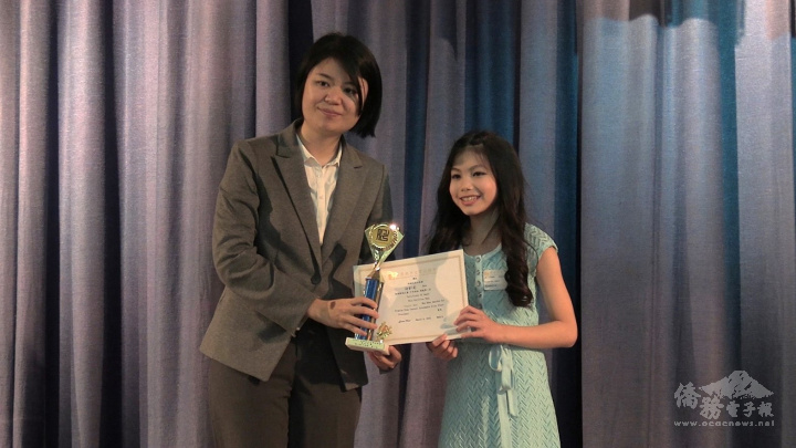 胡凱莉(右)演唱「揮著翅膀的女孩」，獲得中年級第一名，由紐約文教中心副王鈺淇(左)頒獎