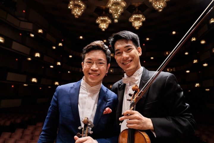 NSO國家交響樂團在美東時間19日以台灣愛樂之名首登華盛頓特區甘迺迪表演藝術中心，由旅美小提琴家黃俊文（左）擔任小提琴獨奏的布魯赫「蘇格蘭幻想曲」是全場第一個高潮，演奏時黃俊文也不時與首席林品任（右）交換眼神，相互支撐樂曲進行。（NSO國家交響樂團提供）