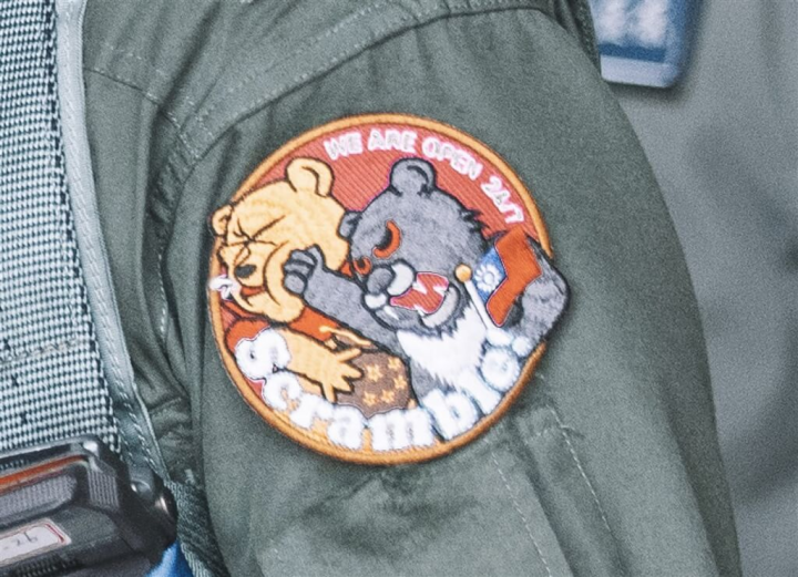 中共持續對台軍演，一名經國號IDF戰機飛官9日執行起飛前檢查，其臂章大秀台灣黑熊手持中華民國國旗，並痛毆小熊維尼，相當有趣。（軍聞社提供）
