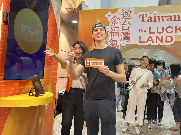 One of the tourist shows the NT$5,000 prize he won at Saturday's press event at Taiwan Taoyuan International Airport.