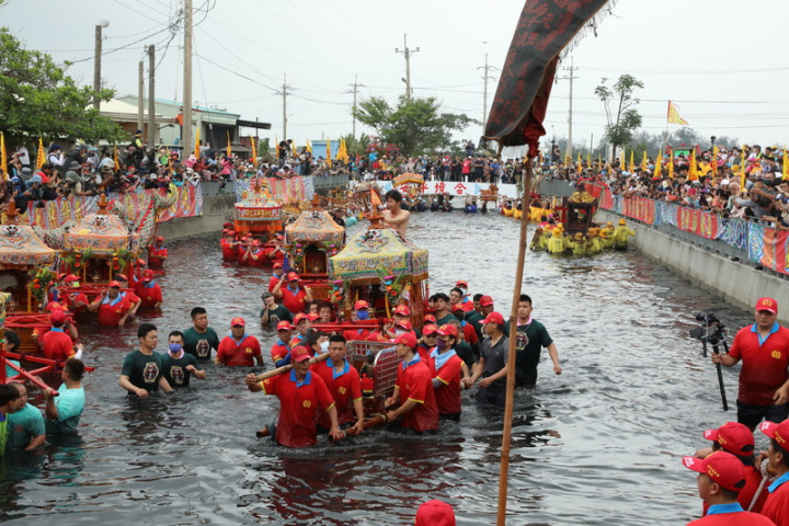 嘉義縣布袋鎮新塭嘉應廟「衝水路、迎客王」活動16日在新塭大排王船碼頭登場，吸引數千名信眾、遊客觀看神轎衝下水迎客王的宗教儀式。