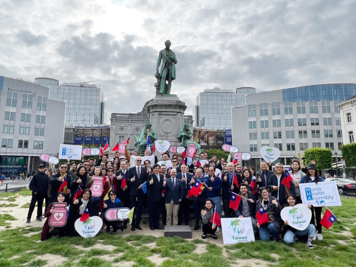 比利時僑團與留學生代表在緊鄰歐洲議會廣場舉行挺台參與WHA活動，100餘人到場聲援，他們高舉標語並呼籲各界支持台灣參與WHA，吸引許多群眾駐足聆聽。（駐歐盟代表處提供）