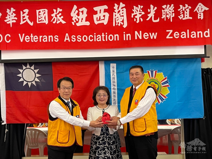 滿任會長李希豪(左)及新任會長余勇才(右)交接印信，由駐奧克蘭辦事處處長陳詠韶(中)監交