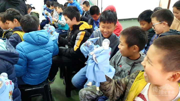 現場學生專注地研究如何運用五指玩布袋戲偶，隨著能操作布偶完成動作，紛紛露出開心歡笑