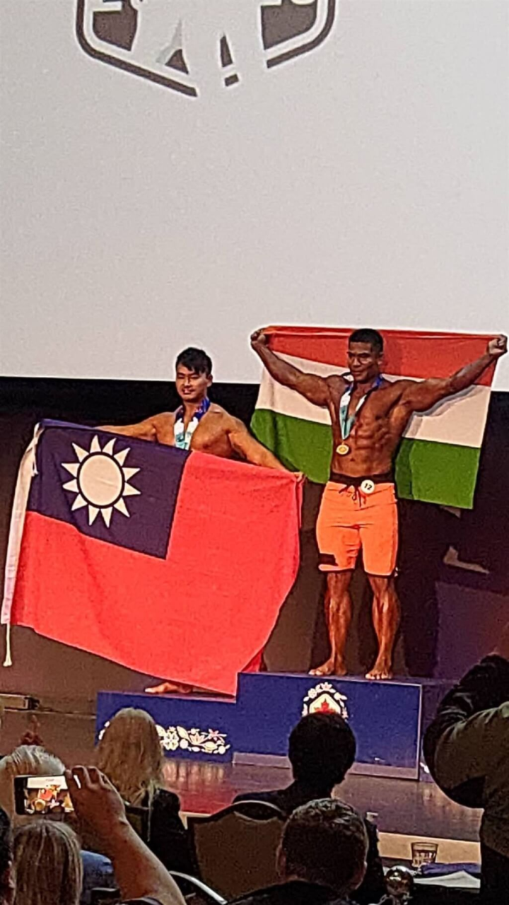 第20屆世界警察消防運動會在加拿大舉行，警政署30日公布首日賽事台灣共奪得3金4銀佳績。南投縣消防局林冠儀（左）於健美及健體項目一舉囊括2面銀牌，帶著國旗上台領獎。（消防署提供）