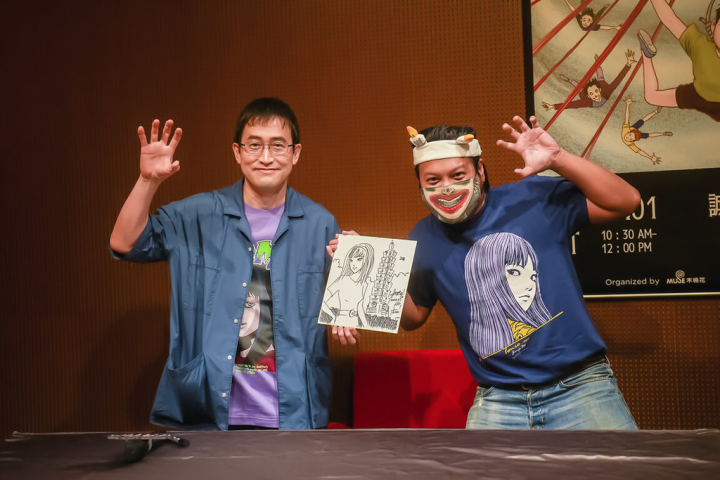 日本恐怖漫畫家伊藤潤二（左）勾勒筆下角色「富江」同框101大樓簽繪板，並在1日見面會上親自抽籤送給幸運粉絲。（木棉花提供）