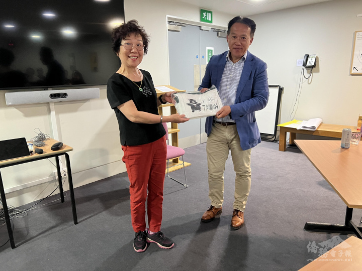 由臺灣大學資深校友、英國僑界重要臺商「我們家旅行社」共同創辦人藍國瑜(左) 僑務諮詢委員致贈臺灣味紀念品