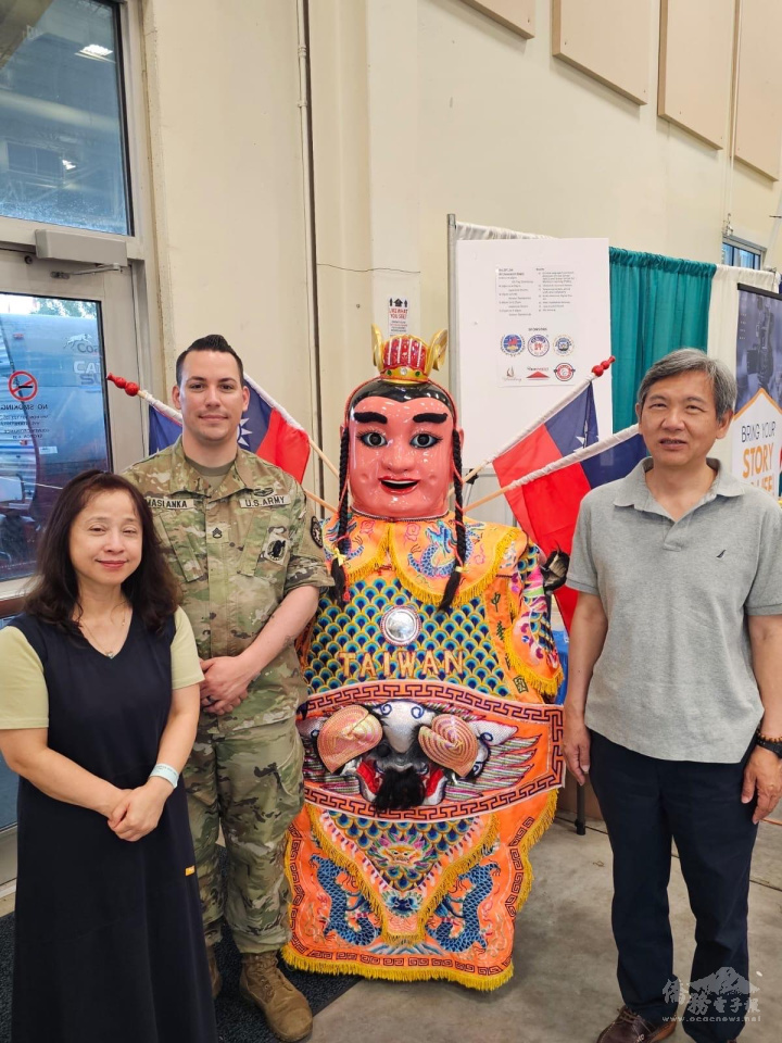 黃世珍(左1)及黃士聰(右1)與美國士兵(左2)在臺灣攤位三太子前合影