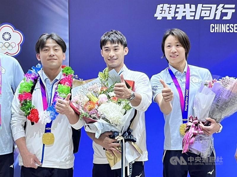 Hangzhou Asian Games gold medalists Yang Yung-wei (center) and Lien Chen-ling (right) pose for the press at Taoyuan International Airport on Sept. 29, 2023.