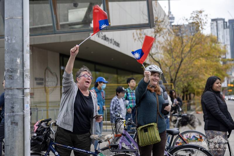 多倫多街頭自行車騎士也停下腳步，揮舞中華民國國旗，為僑界慶祝中華民國112年雙十國慶大遊行隊伍歡呼加油。