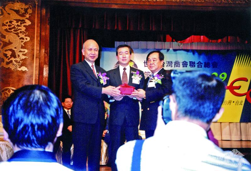 1999年，呂憲治（右）在僑務委員會委員長焦仁和（中）監交下，接任世總第6屆總會長