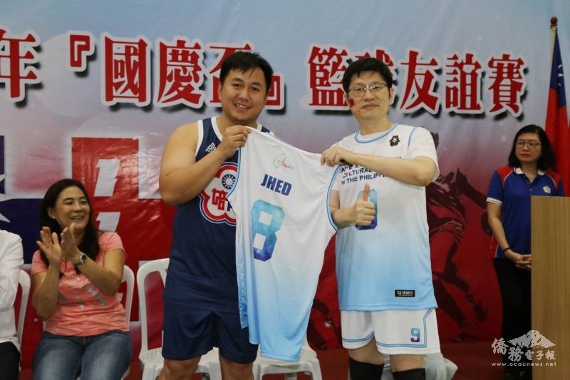 菲華文教中心副主任梁崇偉(右)贈送駐菲代表處籃球隊制服予丁俊峰(左)