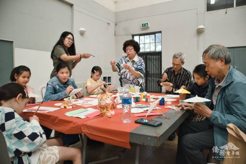 聚精會神彩繪油紙傘，姜依莉(站立者)及章如軍(右)