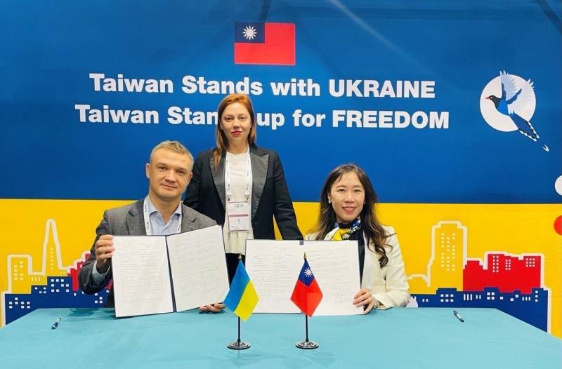 我國駐波蘭大使吳尚年與烏克蘭NGO「NO Labels」執行長哈米亞克（Oleksandr Khomiak，左一）簽署合作瞭解備忘錄，協助治療烏國創傷症候群患者；烏克蘭國會議員詩克綸（Alyona Shkrum，中）出席見證。