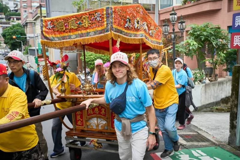 國立政治大學邀請國際學生參與景美集應廟的聯合遶境巡安活動，透過抬神轎參與，體驗台灣的廟宇文化。（政大提供）
