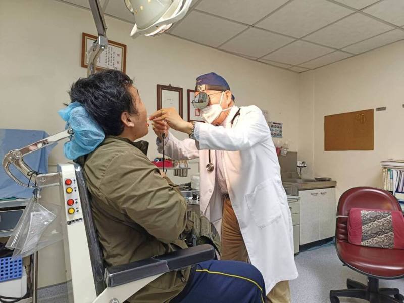 苗栗一名中年男子有3高病史，且長期菸酒不忌，因出現喉嚨痛、聲音沙啞及自覺呼吸困難，由基層診所轉診至為恭醫院，經切片檢查診斷為會厭腫瘤，及時手術撿回一命。圖為為恭醫院耳鼻喉科主任林烱堃（右）看診示意圖。（為恭醫院提供）