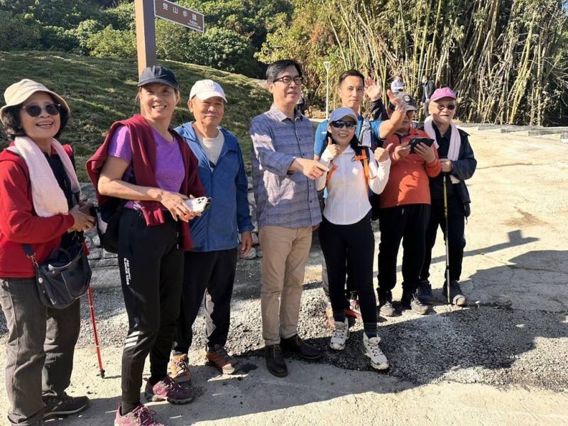 高雄市政府在台泥鼓山預拌廠舊址興建登山口停車場及連接柴山登山步道，31日正式啟用，高雄市長陳其邁（左4）上午視察登山步道，與登山民眾合影。（高雄市政府提供）