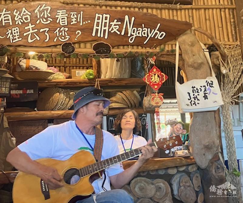 A man playing traditional Amis songs on his guitar. The sign above reads "Ngaàyho," which roughly translates to "Hello."