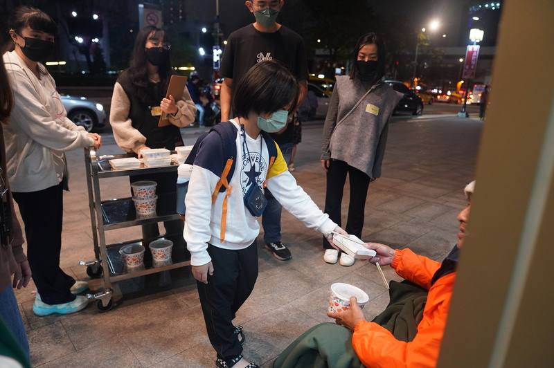 由社團法人人生百味文化建構協會發起的「2024街頭（愛喲）尾牙」20日持續在台北車站周邊進行，現場邀請志工朋友一起推著餐車、分發餐食給街友，有小朋友也加入志工行列送暖