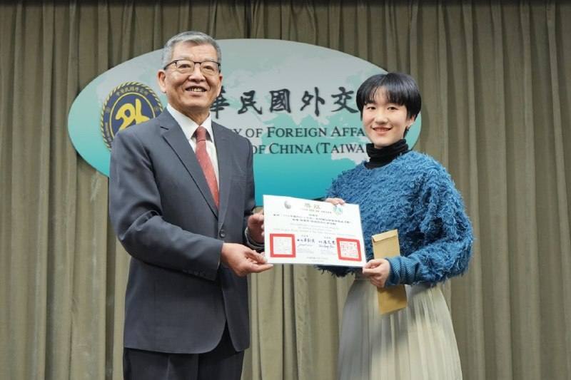 外交部政務次長謝武樵頒發獎狀及獎金予徵文比賽特優獎得主胡懷宇同學。